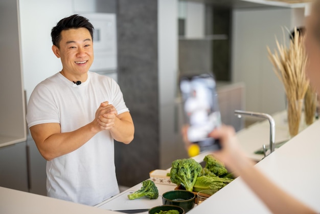 Mulher grava um vídeo no smartphone do homem cozinhar salada