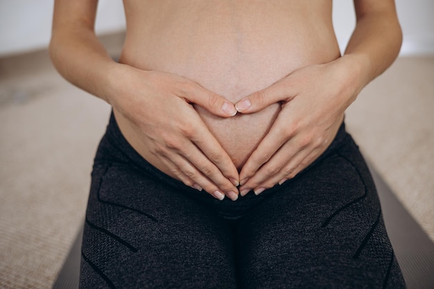 Mulher grávida abraçando a barriga com as mãos