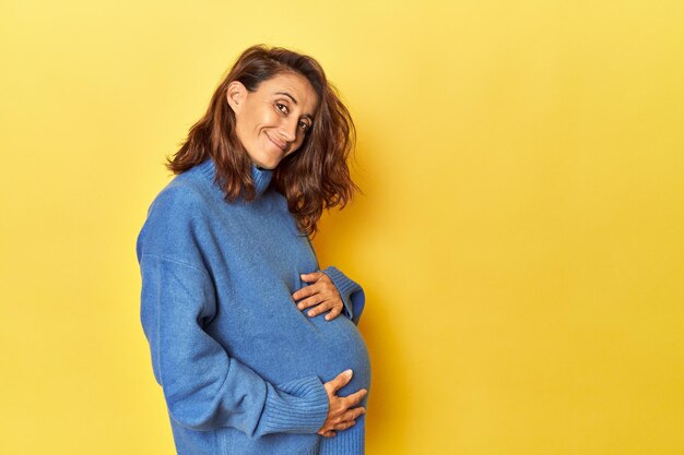 Mulher grávida acariciando sua barriga em amarelo
