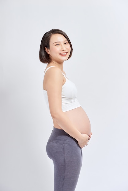 Mulher grávida acariciando sua barriga sobre fundo branco