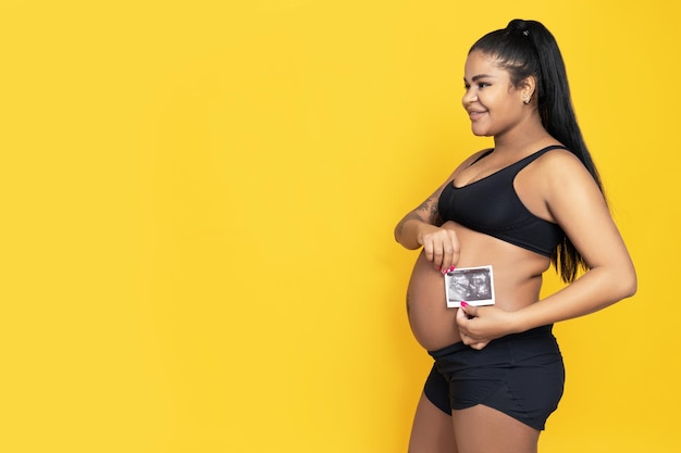 Foto mulher grávida afro-americana em fundo amarelo