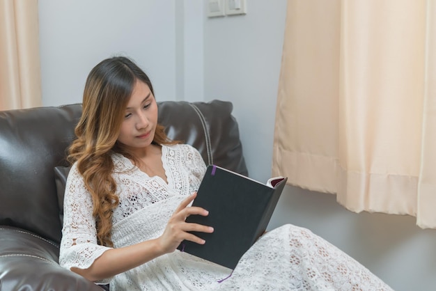 Mulher grávida asiática leu um livro em casaEstudo de como criar filhosTailândia