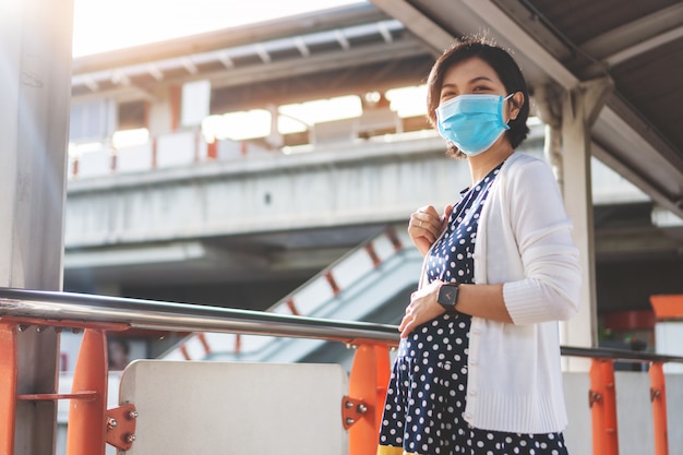 Foto mulher gravida asiática na máscara protectora no aeroporto