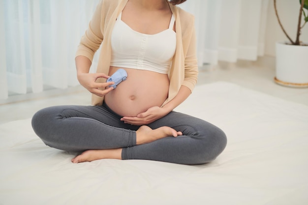 Mulher grávida atraente está deitada na cama com carro de brinquedo na barriga É um menino Últimos meses de gravidez