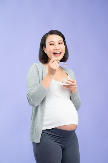 Mulher grávida bonita asiática comendo iogurte