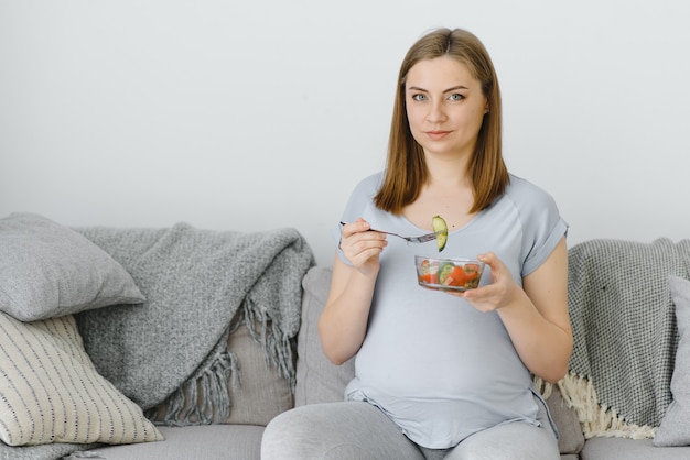 Mulher grávida bonita e saudável comendo salada de vegetais