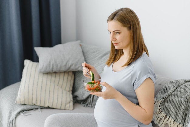 Foto mulher grávida bonita e saudável comendo salada de vegetais