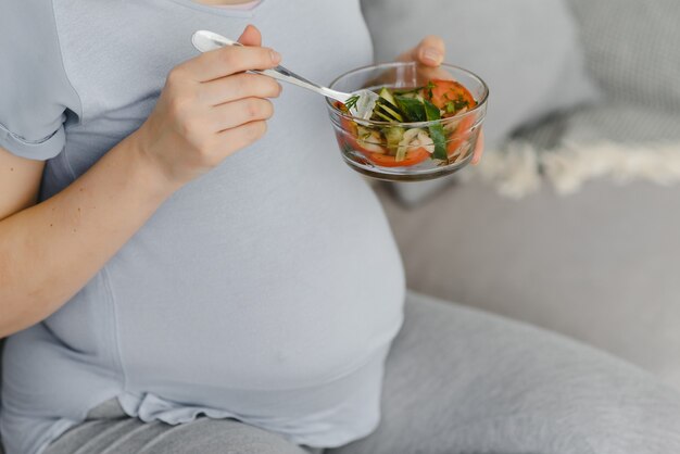 Mulher grávida bonita e saudável comendo salada de vegetais