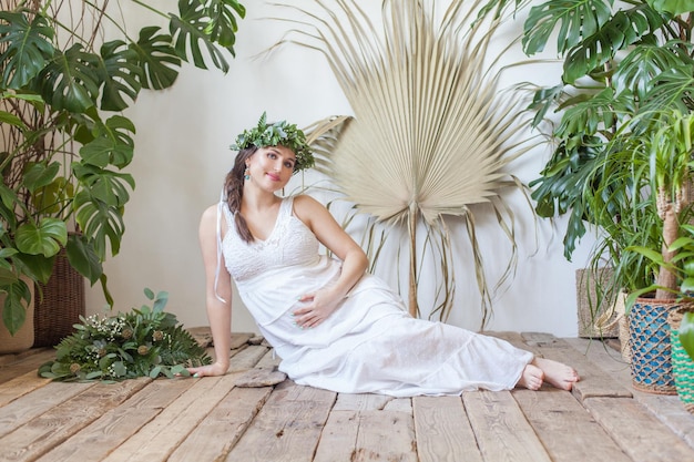 Mulher grávida bonita em vestido branco de algodão em fundo de natureza rural