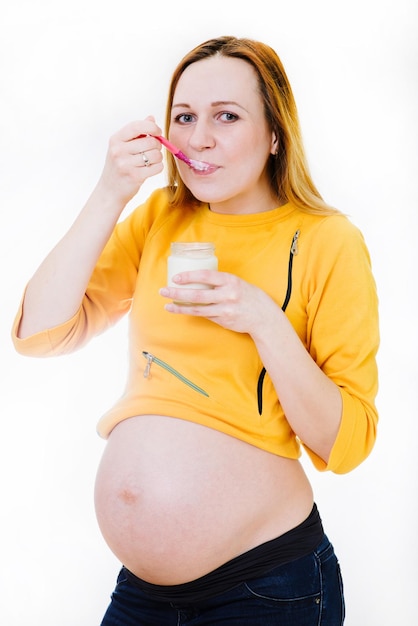 Mulher grávida caucasiana com copo de iogurte isolado em branco