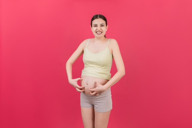 Mulher grávida coçando a barriga no fundo colorido