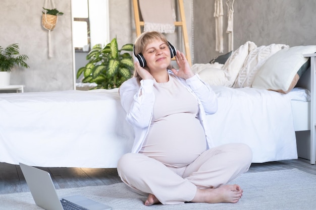 mulher grávida com barriga grande gravidez avançada em fone de ouvido sem fio ouvindo música