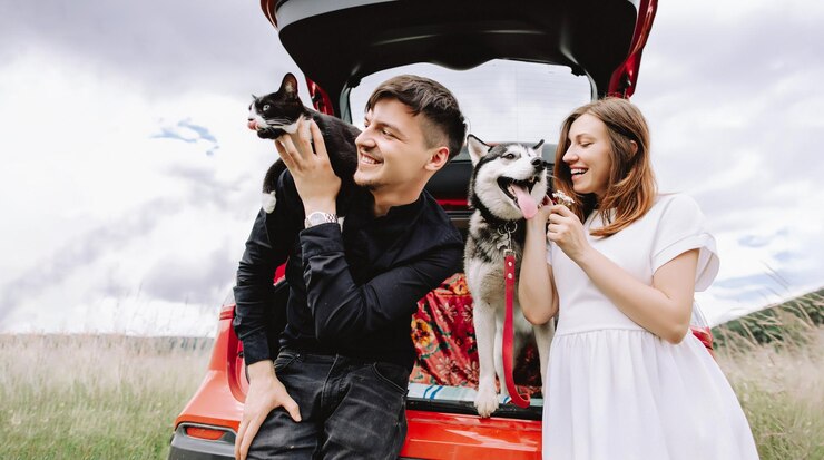 Mulher grávida com husky e gato nos ombros do homem perto do carro Conceito de viagem com animais de estimação