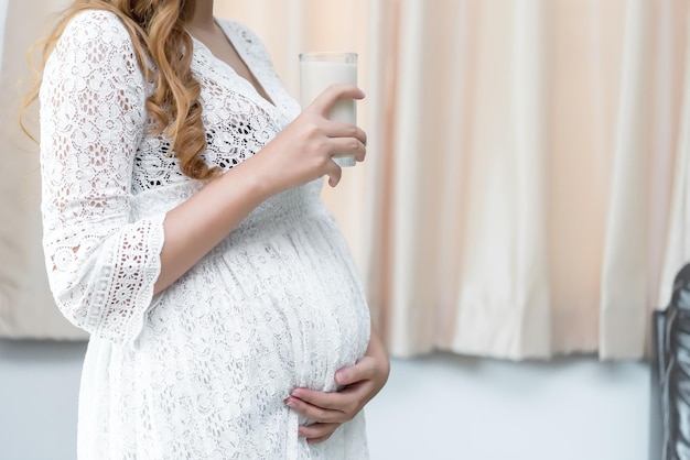 Mulher grávida com leite na mãoBeber leite é uma boa saúde para a gravidez