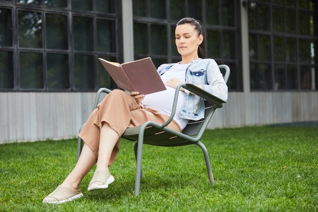 Mulher gravida com livro que aprecia o verão