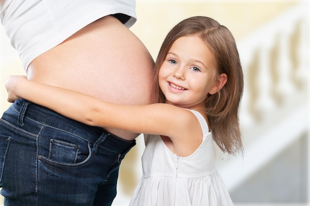 Mulher grávida com sua filha ouvindo o bebê na barriga