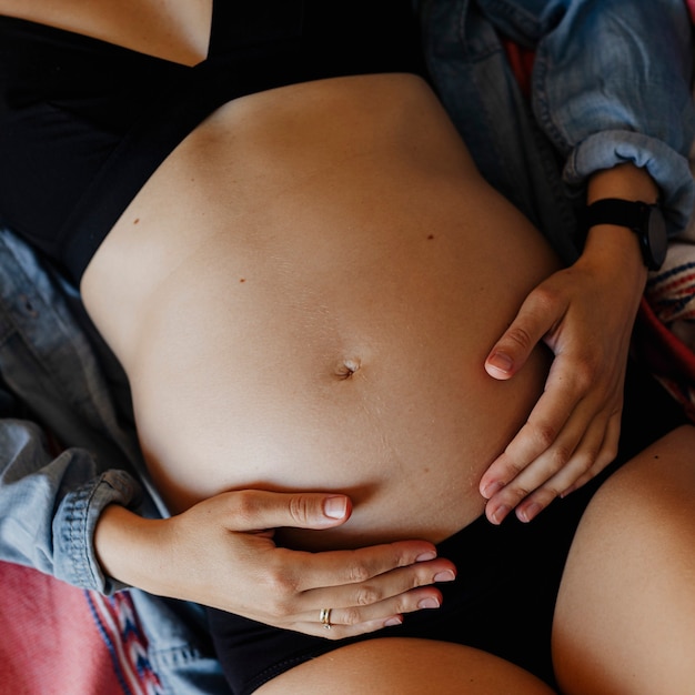 Foto mulher grávida com uma cueca preta deitada em um sofá cinza