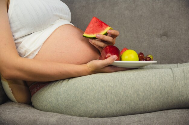 Foto mulher grávida come fruta melancia maçã uva