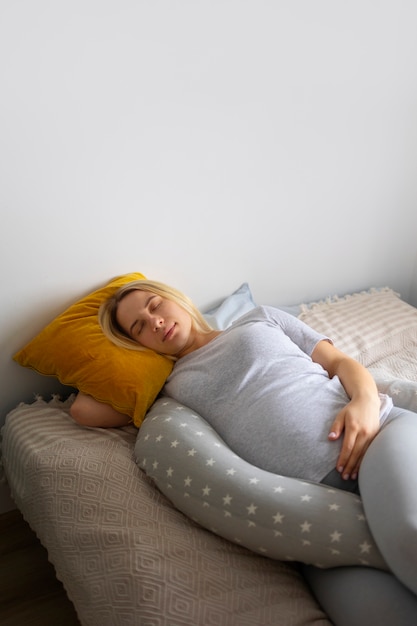 Foto mulher grávida de alto ângulo usando travesseiro de amamentação