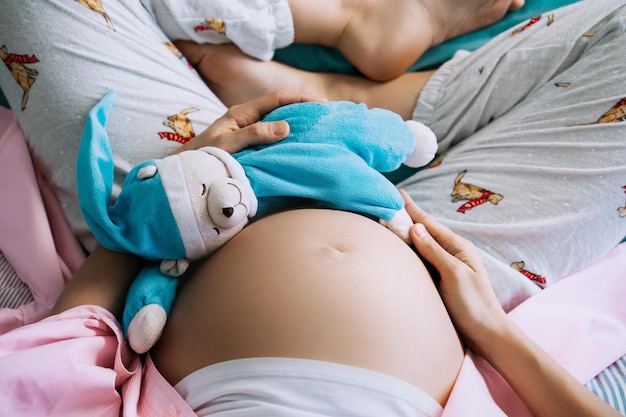 Foto mulher grávida de close-up barriga com ursinho de pelúcia conceito de parentalidade maternidade preparar e esperar pelo bebê mãe grávida feliz durante a gravidez