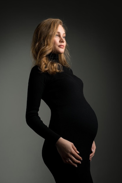 Mulher grávida de vestido preto no estúdio