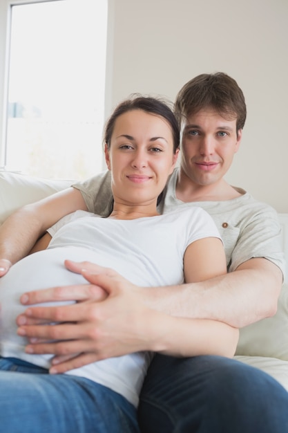 Mulher grávida deitada no sofá com parceiro