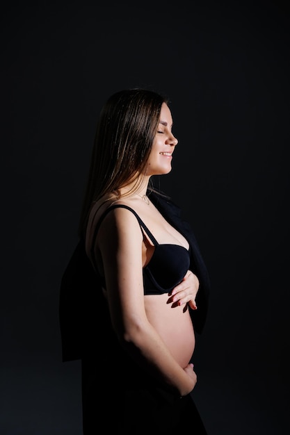 Mulher grávida elegante Linda garota grávida com cabelos longos em terno preto no conceito de fundo cinza de gravidez feliz e família