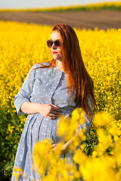 Mulher grávida em campo amarelo