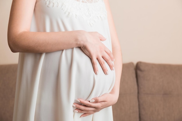 Mulher grávida em lindo vestido em pé em casa