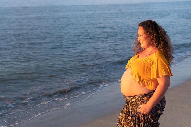 Mulher grávida em pé na praia