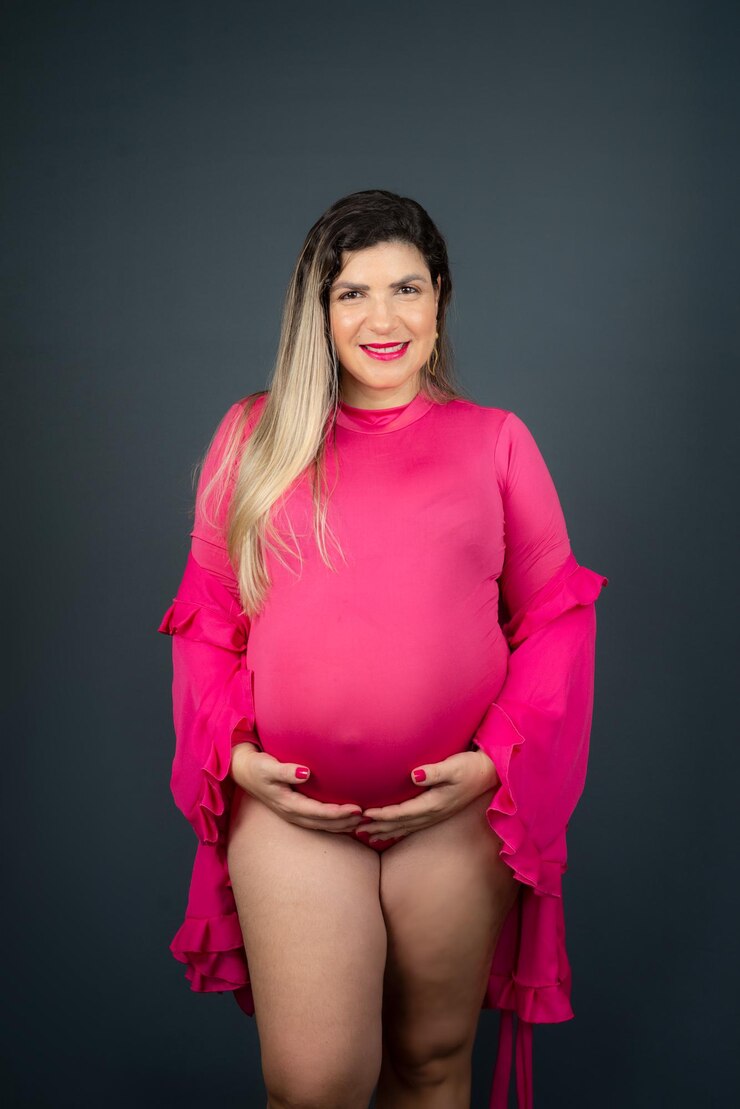 Foto mulher grávida em pé posando para foto em estúdio isolado contra fundo cinza