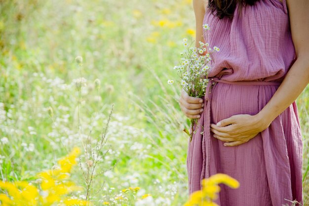 Mulher grávida em um vestido rosa em um campo