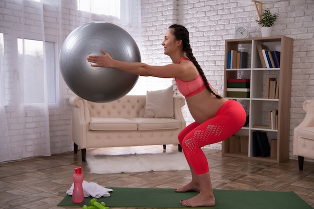 Mulher grávida está treinando a barriga com bola em casa