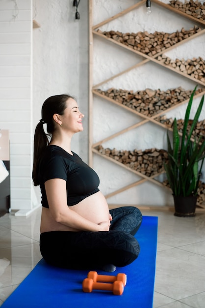 Mulher grávida exercitando ioga em casa. ioga na gravidez e fitness.