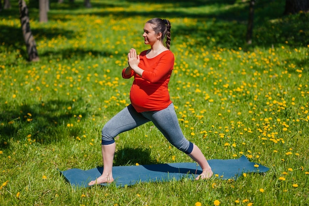 Mulher grávida fazendo asana ao ar livre