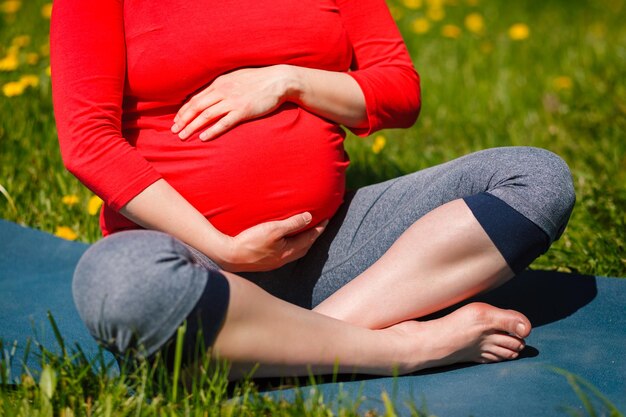 Mulher grávida fazendo asana sukhasana ao ar livre