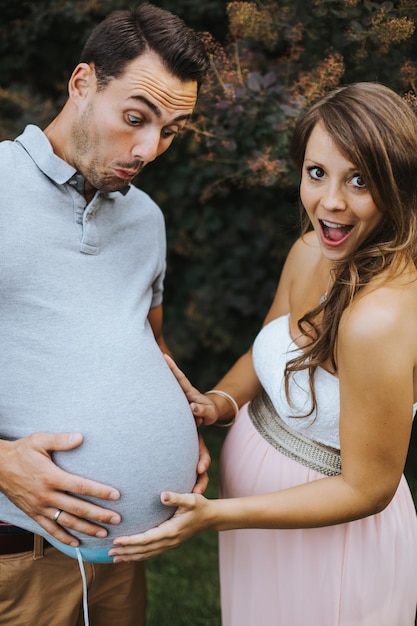 Mulher grávida fazendo cara enquanto segura o estômago do marido