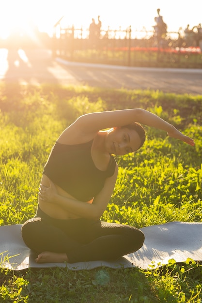 Mulher grávida fazendo exercícios de fitness na grama num dia de verão. Estilo de vida saudável.