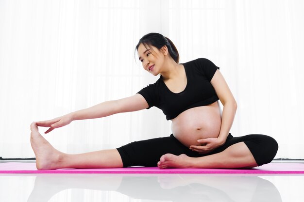 Foto mulher grávida fazendo exercícios de ioga na sala de estar em casa