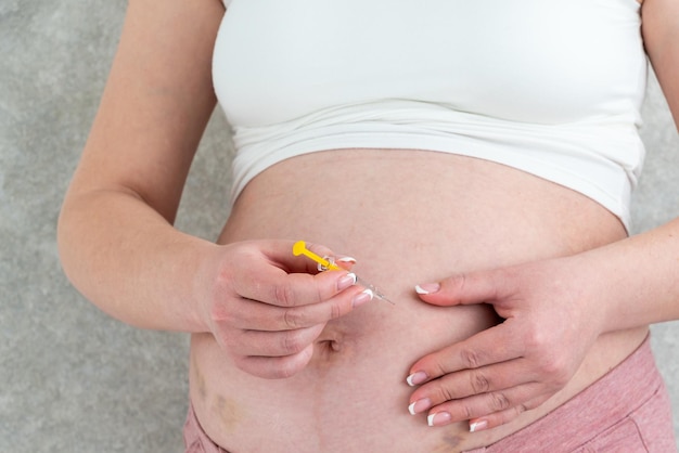 Mulher grávida fazendo injeção no estômago