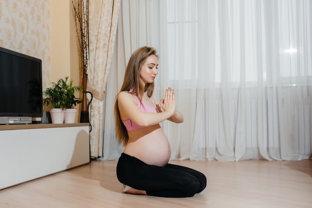 Mulher grávida fazendo ioga em casa