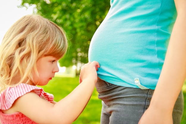 Mulher grávida feliz com um bebê na natureza no parque