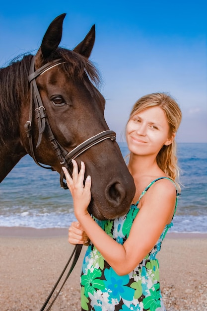 Mulher grávida feliz com um cavalo na praia no verão na natureza