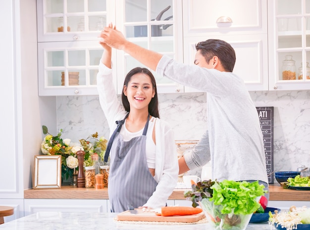 Mulher grávida feliz dançando com o marido na cozinha