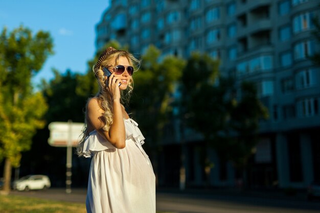 Mulher grávida feliz e caucasiana ligando para smartphone em streen na cidade