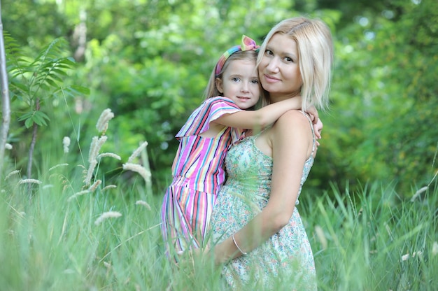 Mulher grávida feliz e filha posando no parque de verão