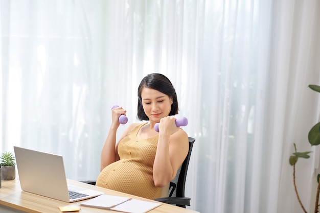 Mulher grávida feliz no escritório sendo ativa