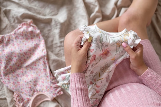 Mulher grávida guarda roupas para bebê recém-nascido. Vista do topo. Copiar espaço