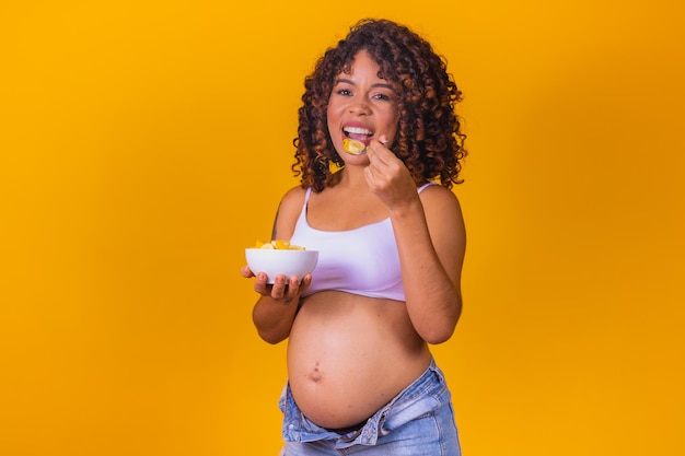 Mulher grávida jovem comendo frutas.