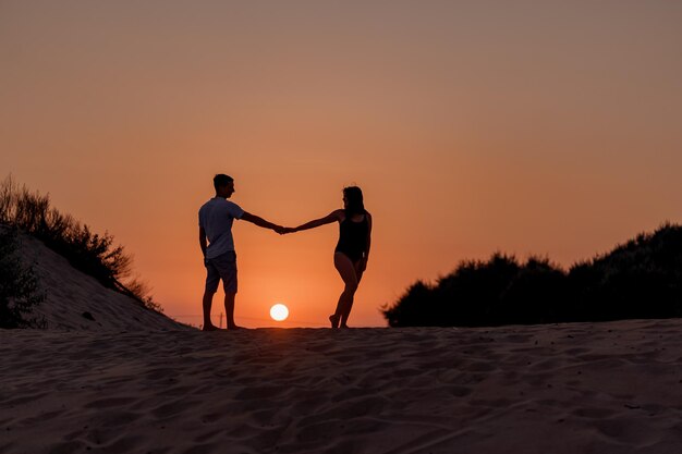 Mulher grávida jovem família ao pôr do sol na praia